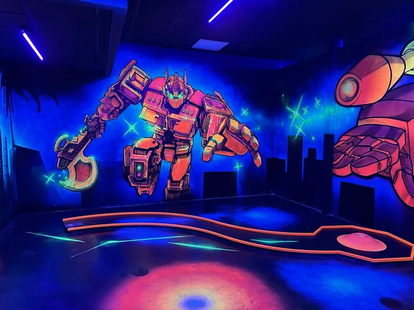 Großer leuchtender Roboter an der Wand einer Schwarzlicht-Minigolfbahn